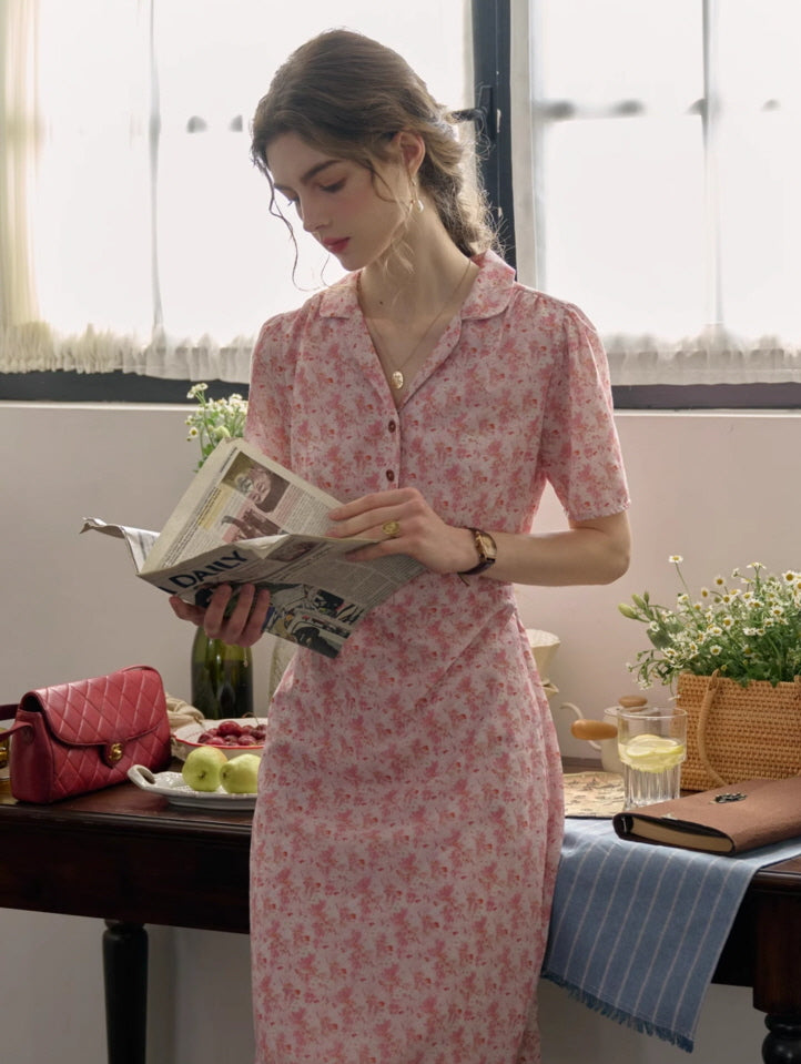 A woman wearing a pink floral cottagecore dress, styled for a casual and romantic moment while reading in a sunlit kitchen setting.