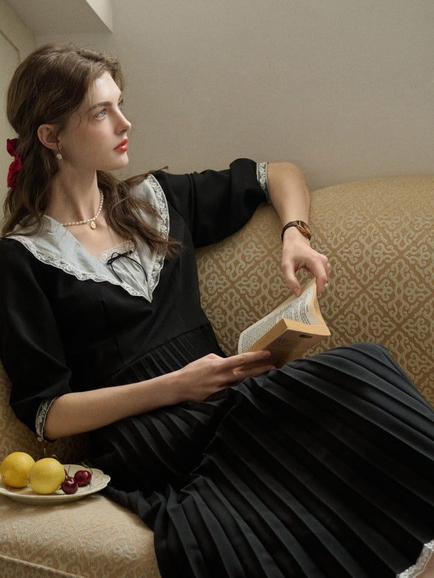 A woman in a dreamy retro black dress with a pleated skirt and lace detail, creating an aesthetic and relaxed fairytale-inspired atmosphere.