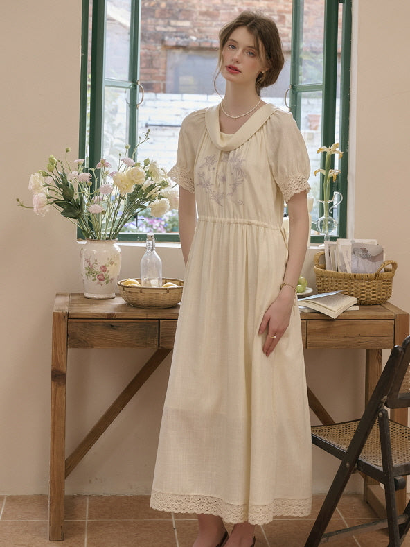 Woman wearing a romantic vintage cottagecore dress with floral embroidery and lace sleeve accents, standing by a sunlit wooden table decorated with flowers, exuding a soft retro aesthetic.