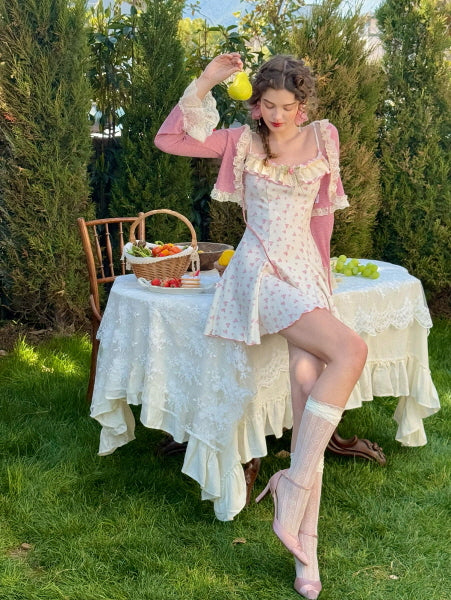 A whimsical cottagecore-inspired scene featuring a young woman sitting at a vintage lace-covered table adorned with a fruit basket and a green pear.