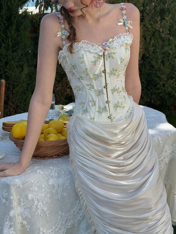 Close-up of cream ruched satin skirt paired with floral embroidered corset top, styled on a lace-covered picnic table with lemons – romantic cottagecore-inspired outfit for women