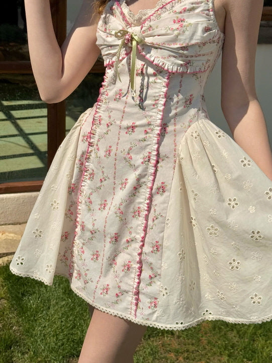 Close-up of floral mini dress with delicate lace trim, ruched bodice, and embroidered eyelet skirt. Feminine coquette style with romantic ribbon bow detail and vintage charm.