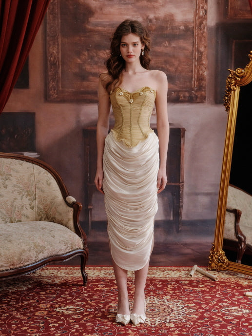 Front-facing full body shot of a model in a gold floral corset and ruched ivory skirt, styled in a fairytale-themed room with red carpet and vintage furniture for a graceful and elegant silhouette.