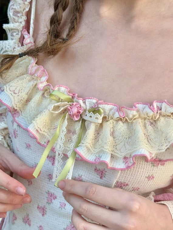 Detailed shot of a lace-trimmed neckline with pastel ribbons and floral embroidery, highlighting intricate craftsmanship.