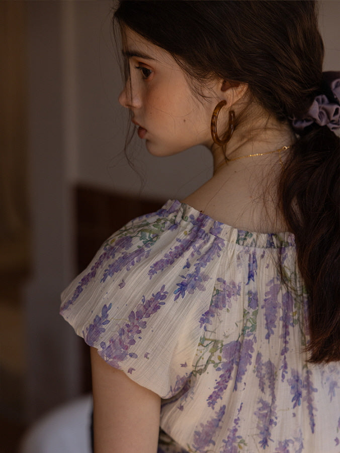 Close-up of a lavender floral dress with delicate ruffled sleeves, showcasing a soft, romantic cottagecore aesthetic against a muted indoor backdrop.