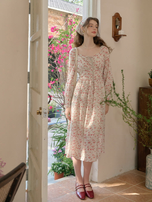 Woman in a cottagecore floral dress standing indoors, wearing a matching headscarf, with retro and aesthetic style details.