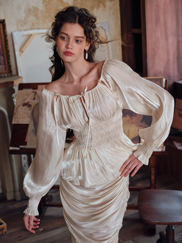Standing confidently in a vintage-inspired satin blouse and ruched skirt, the woman poses in an art-filled studio, blending elegance with an ethereal, fairytale atmosphere.