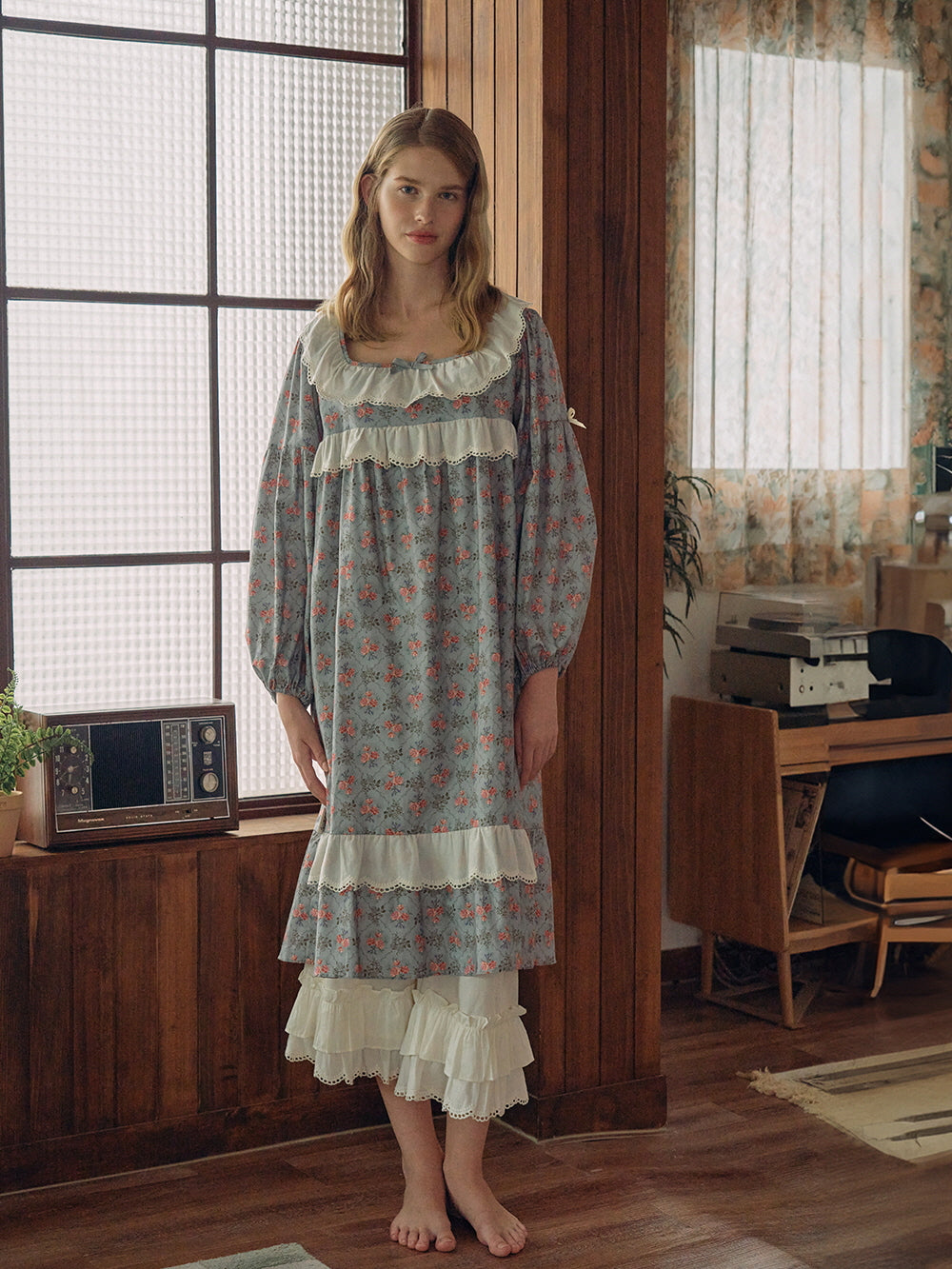 A full-length view of a blue floral nightgown with lace ruffle detailing and tiered hem, exuding a fairytale-like, romantic cottagecore style.