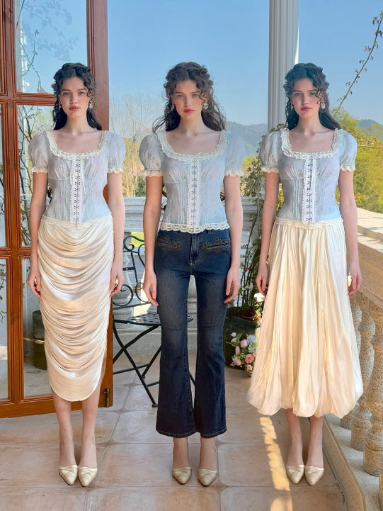 Three models display different styling options for a pastel blue floral corset top with lace trim and puff sleeves.