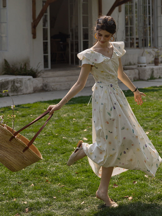 Young woman in a flowing floral dress with flutter sleeves, playfully swinging a straw basket filled with branches, evoking a cottagecore aesthetic in a serene garden setting.