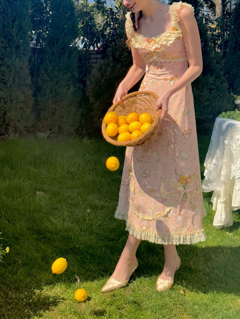 Whimsical cottagecore-style dress adorned with floral lace and bow accents, paired with a wicker basket of oranges, evoking a nostalgic summer picnic scene.