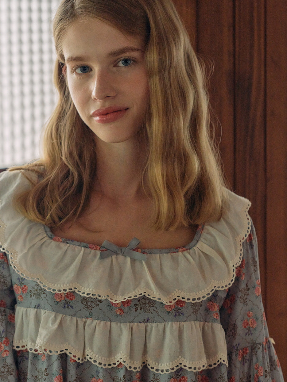 A soft, romantic look featuring a model wearing a blue floral nightgown with lace ruffles and a satin bow, exuding a dreamy, fairytale charm.