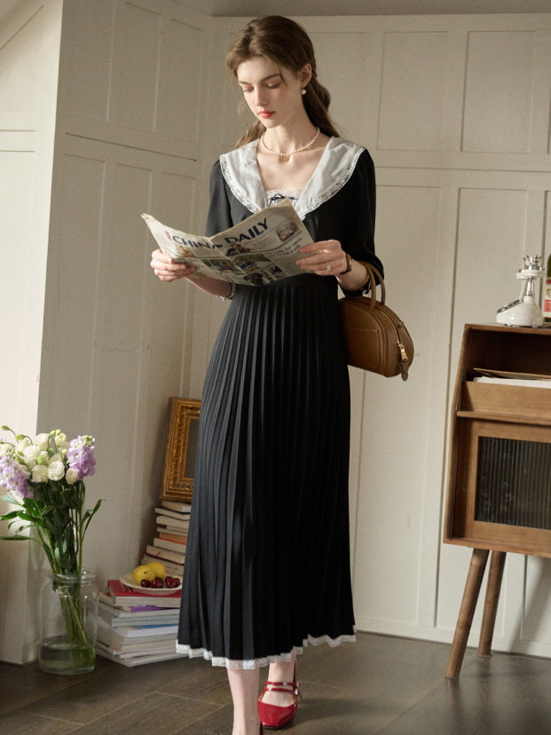 A woman wearing a romantic retro black dress with a lace-trimmed collar and pleated skirt, styled for a casual and aesthetic outfit in a fairytale-inspired room.