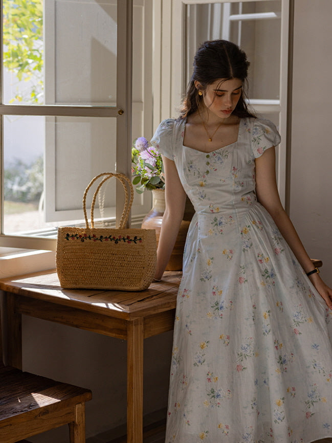 Ethereal floral dress with cap sleeves and a flattering sweetheart neckline, styled in a sunlit room with a woven basket and vintage-inspired cottage decor, exuding a soft, fairytale ambiance.