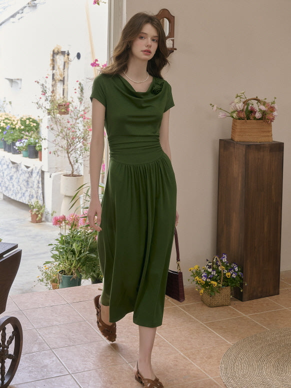 Model in a forest green midi dress with a soft draped neckline and flowing skirt, walking elegantly indoors with a vintage-inspired handbag. Cottagecore and fairytale aesthetic.