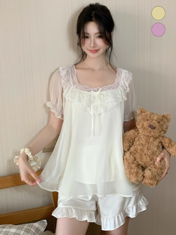 Young woman holding a teddy bear while wearing a romantic chiffon pajama set with frilled shorts and sheer sleeves, styled in soft coquette tones.