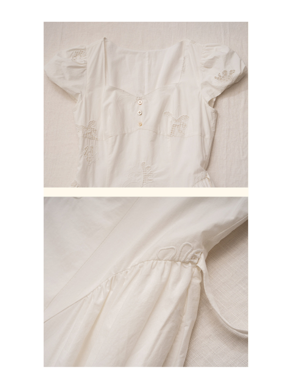 A flat lay of a white dress with cap sleeves, featuring floral lace embroidery and a soft, airy texture, displayed on a beige linen backdrop.