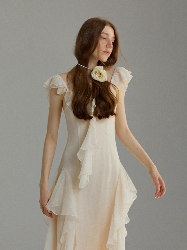 Ethereal ivory dress with flutter sleeves and asymmetrical ruffle layers, styled with a floral choker on a model, expressing a romantic vintage-inspired silhouette.