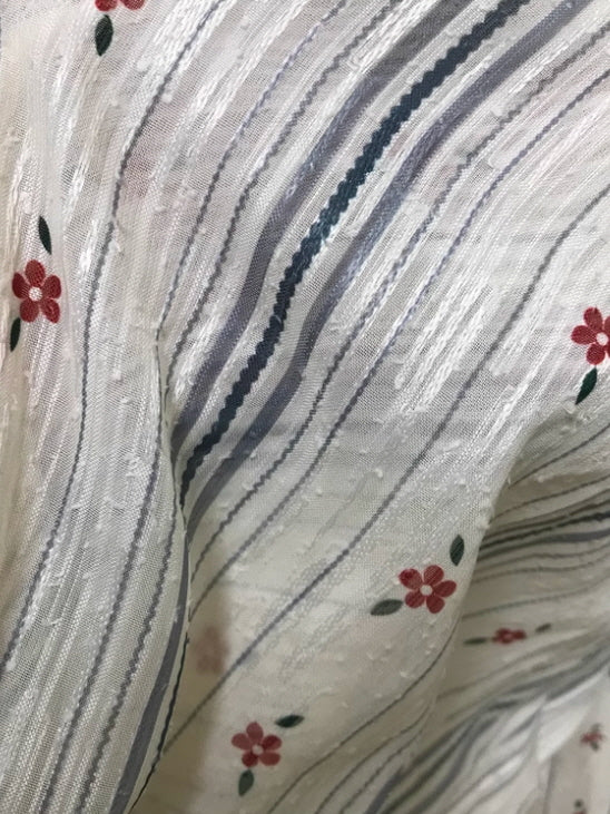 Detailed fabric view of a fairytale-style vintage dress, featuring textured stripes and delicate small red flowers, highlighting the romantic and dreamy aesthetic.