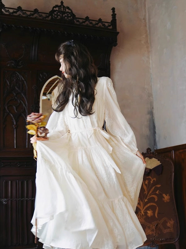 A woman in a flowing vintage-inspired fairytale dress holding dried flowers, standing gracefully in an antique room. Aesthetic and fantasy mood captured in soft lighting.