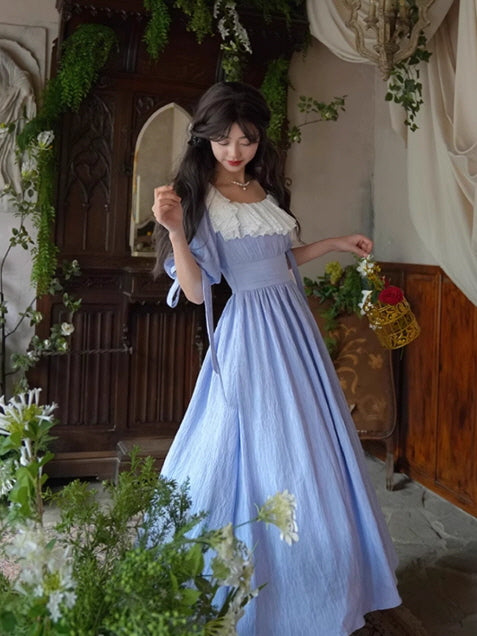 Romantic vintage fairytale dress with a white lace neckline and a dreamy blue skirt, styled in an elegant fantasy outfit among floral decorations