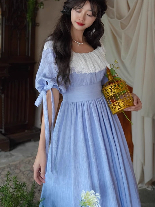 A romantic scene of a woman in a fantasy vintage blue dress with a white lace collar, holding a small golden birdcage, surrounded by flowers. Fairytale, dress, vintage, aesthetic, outfits.