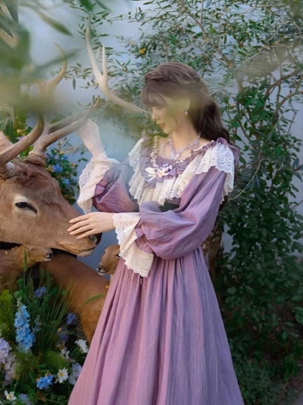 A fairytale-inspired outfit featuring a vintage purple dress with cream lace ruffles, worn by a woman gently touching a deer's antlers in a garden full of flowers, creating a fantasy aesthetic.