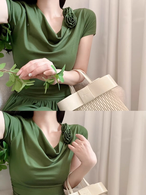 Close-up view of a woman wearing a forest green draped neckline dress with a rose brooch, holding a light beige woven handbag. Natural and delicate styling with a soft romantic mood.