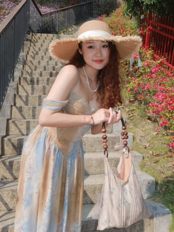A woman in a vintage-style corset dress with a wide-brimmed straw hat, embodying a whimsical princesscore vibe while posing on garden stairs.