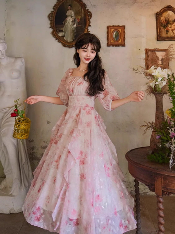 A dreamy pink floral gown with layered ruffles and puff sleeves, styled with a gold birdcage, exuding a whimsical and romantic aesthetic.