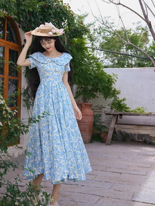 A fairytale-like blue floral gown with a delicate peter pan collar and cinched waist, capturing a romantic princesscore aesthetic in a garden setting.