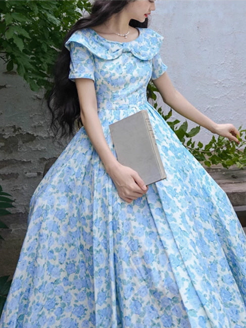 Close-up of a blue floral dress with a wide, vintage-inspired collar and puff sleeves, paired with a classic book for a romantic cottagecore aesthetic.