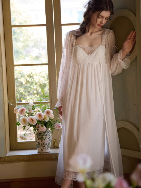 Wearing a long white nightgown with lace trim, the model leans by the window, framed by pastel blooms in a serene princesscore atmosphere.