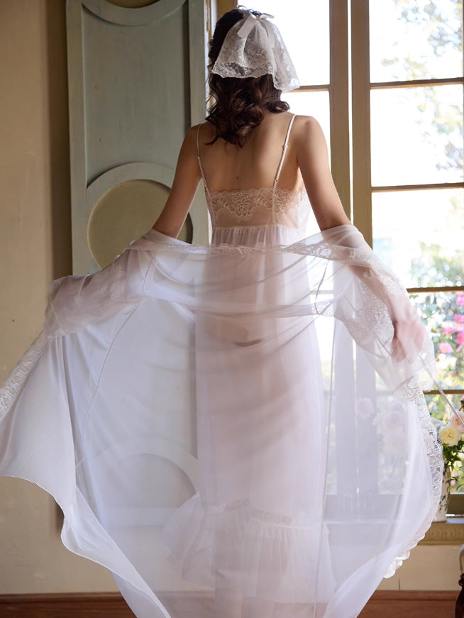 Back view of a model in a romantic sheer robe and ivory lace slip dress, holding the flowing hem in soft light, evoking a dreamy princesscore mood.