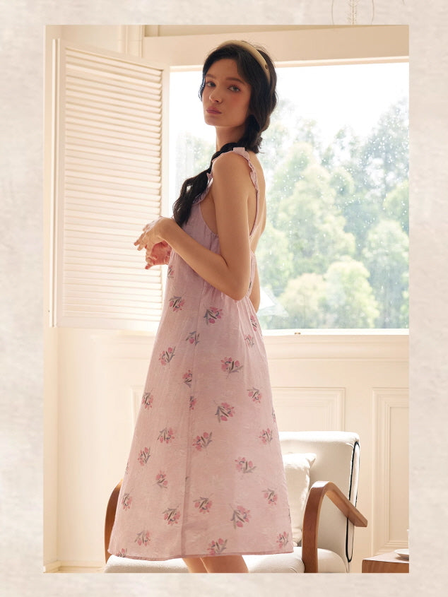 Model stands by the window in a light pink midi nightdress with floral print and ruffled straps, evoking a romantic and elegant fairycore mood.