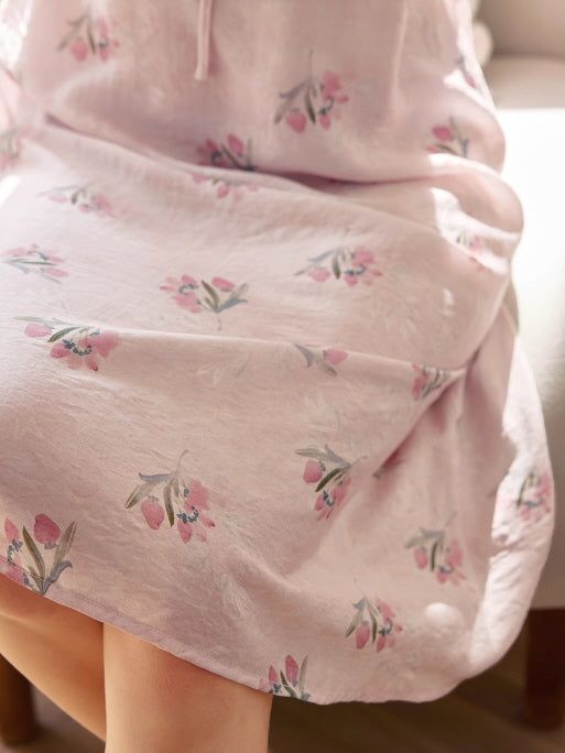 Close-up of soft pink fabric with delicate floral prints, showcasing the vintage-inspired texture and dreamy loungewear design.