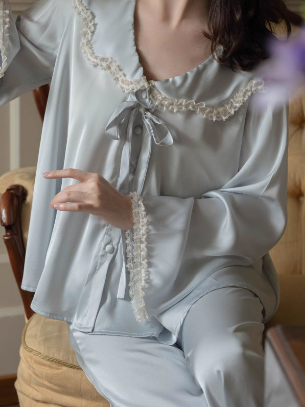Close-up of powder blue loungewear top with oversized lace-trim collar, ribbon bow tie and covered buttons, romantic vintage coquette sleepwear detail.