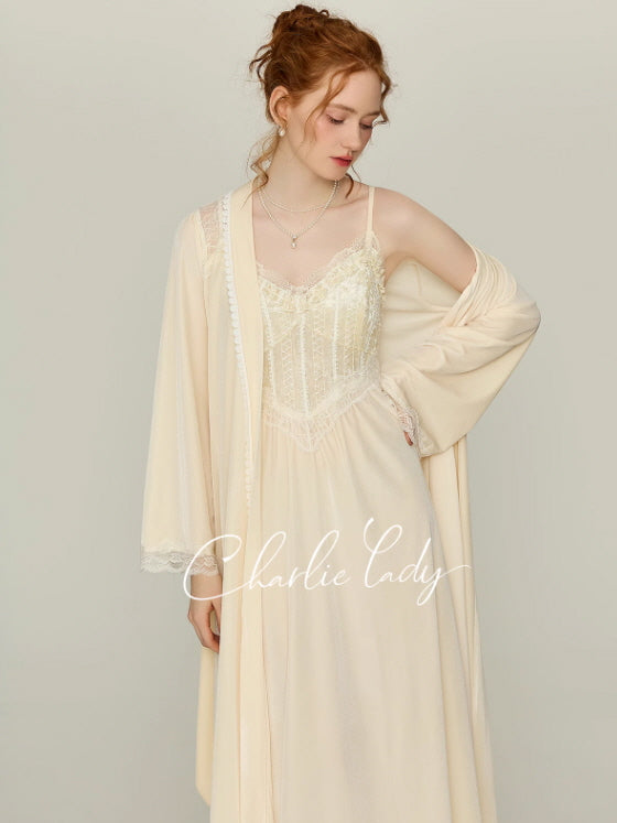 Model styling an ivory lace corset nightgown with a matching long sleeve wrap robe and tie belt, vintage-inspired princesscore loungewear look in a soft studio setting.