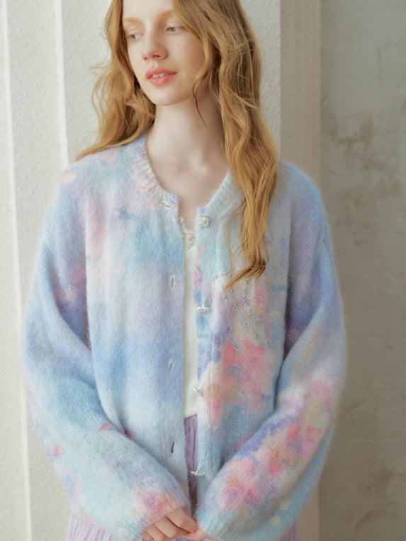 Pastel watercolor knit cardigan with soft blue and lavender tones, featuring delicate button details and subtle bead embroidery, styled in a romantic cottagecore and fairycore aesthetic.