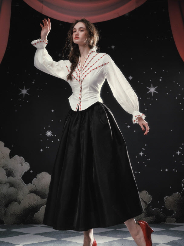 A romantic ivory blouse with ribbon embroidery and puffed sleeves, styled with a flowing black skirt, photographed in a dreamy fairytale-inspired setting with soft lighting and classic vintage elegance.