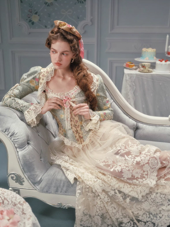 Romantic vintage floral corset with lace trim and pink ribbon detail, styled with a sheer lace skirt in a soft cottagecore and fairycore inspired interior setting.