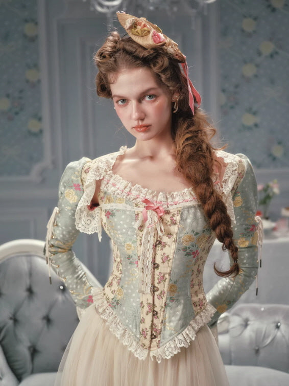 Vintage-inspired floral corset top featuring lace-edged neckline, pastel green floral panels, and adjustable waist shaping, creating an elegant cottagecore fairytale look.