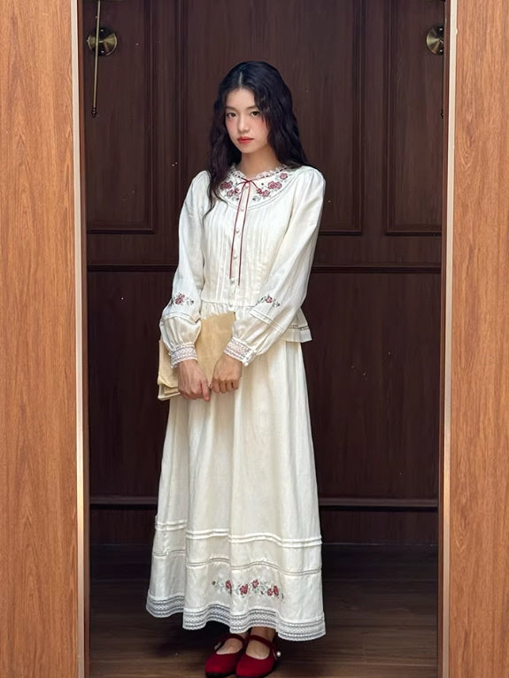 A woman wearing a white vintage embroidered blouse styled with a matching long skirt, featuring rose embroidery and lace details in a romantic cottagecore aesthetic outfit.