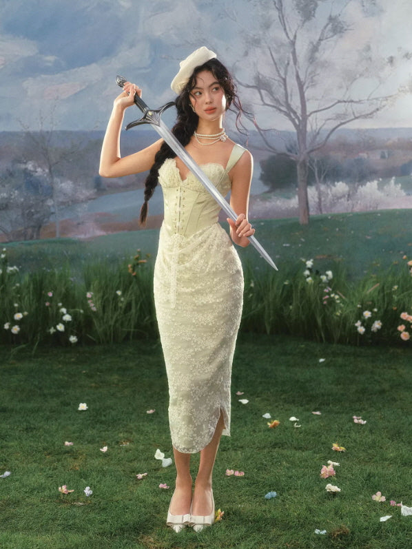 Elegant sage green corset dress with lace overlay and midi silhouette, styled in dreamy garden setting