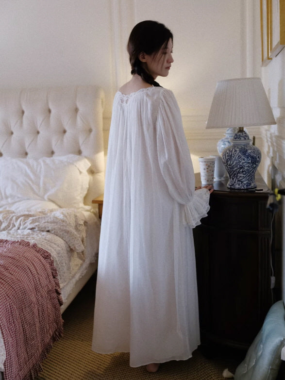 Back view of flowing white nightgown with loose silhouette and delicate lace trim in cozy bedroom setting