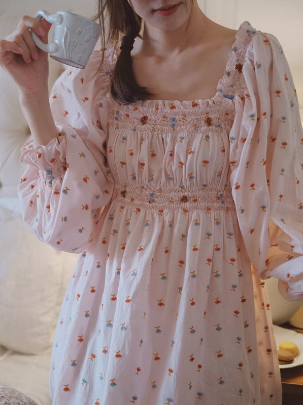 Close-up of smocked neckline and long puff sleeves on pink floral cotton nightgown, soft texture and delicate detailing