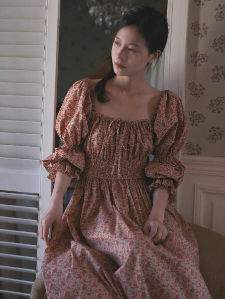 woman sitting in warm vintage room wearing red floral cottagecore dress, soft feminine mood