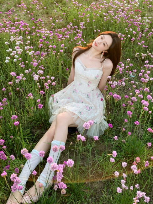 Ivory floral lace corset mini dress with pink flower print, worn in a blooming wildflower field for a fairycore summer look