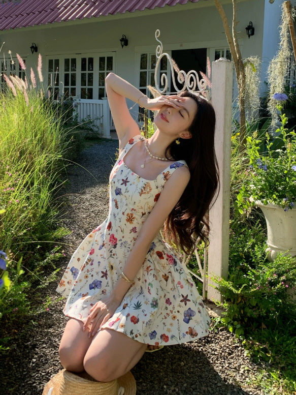 Romantic cream botanical fairycore mini dress with colorful floral print, styled outdoors in a summer garden