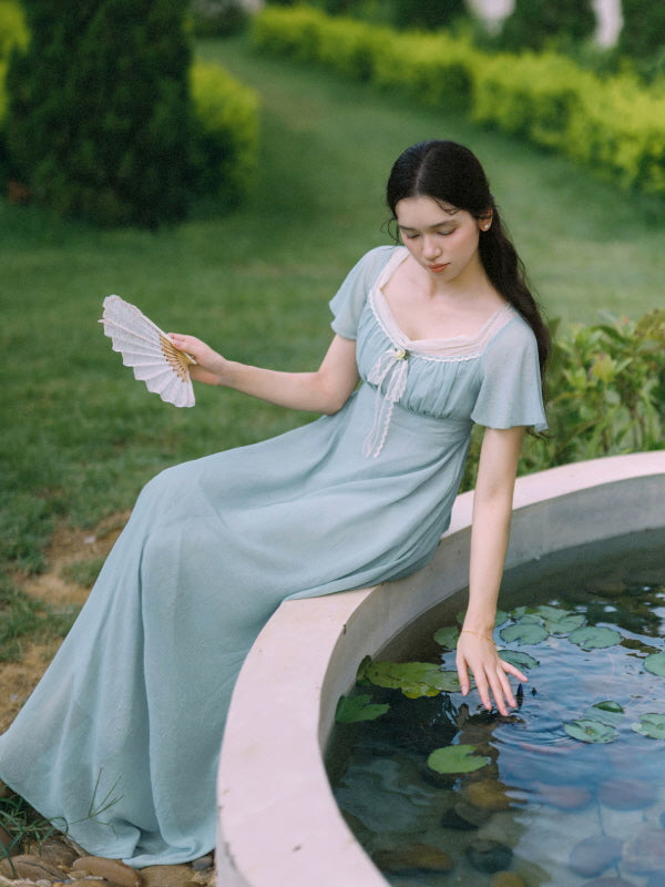 Cottagecore blue maxi dress styled beside a garden pond with folding fan